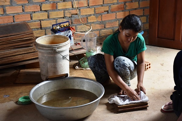 バナナの繊維を水に溶かし、紙すきをする10代の女性スタッフ