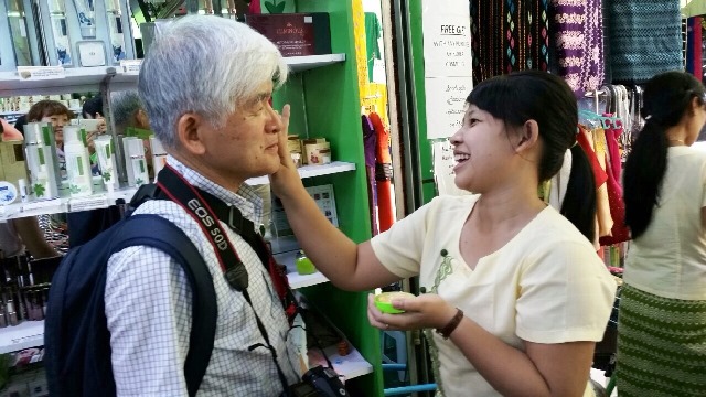 ヤンゴンのマーケットでミャンマーの子どもや女性が使う日焼け止め兼化粧品の「タナカ」を試しに塗ってもらう様子。懐の深いミャンマー人は微笑むとみんなはにかんだ素敵な笑顔を浮かべてくれる。昔の日本人を感じさせるような控えめな人が多い