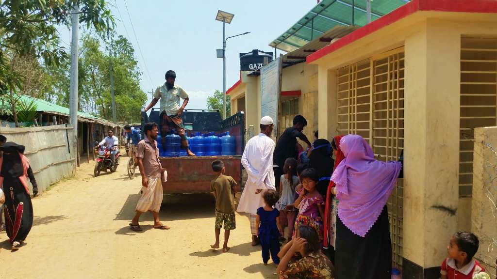 炎天下の中、NGOからが配給する飲料水を待つロヒンギャの人たち。女性と子どもが多いのが印象的だった（レダ難民キャンプ）