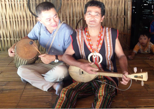 カトゥー族の伝統的な楽器を演奏する村一番の「楽器の達人」。隣はハノイ大学少数民族研究所の調査員