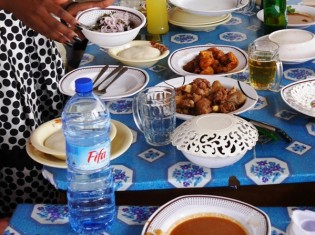 西アフリカの国ベナンのレストランの食卓。左奥にある白い餅のような食べ物がフフ（ベナンでは「アグ」と呼ぶ）。中央に並ぶ魚や肉、スープと一緒に食べる（ベナン・コトヌーで撮影）