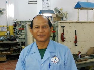 カンボジア・シェムリアップのリハビリセンターで義足を作るキム・エアンさん。後ろは工房
