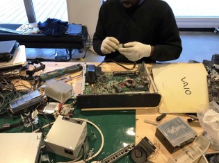 ピープルポートのオフィスで小型電子機器をていねいに解体する西アフリカ出身の難民申請者の社員（ピープルポート提供）