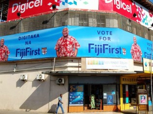 商業ビルの一面に掲げられた「フィジー・ファースト」の広告。現首相のバイニマラマ党首を大きく取り上げ、投票を呼びかける。看板は英語、フィジー語、ヒンディー語に対応
