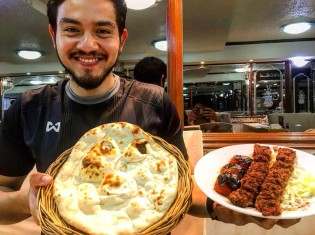 イラク料理「イラク・レストラン・バンコク」の2代目経営者のアナン・コシサギさん。両手に持つのは、店で一番人気のビーフケバブとナンのセット（店内で撮影）