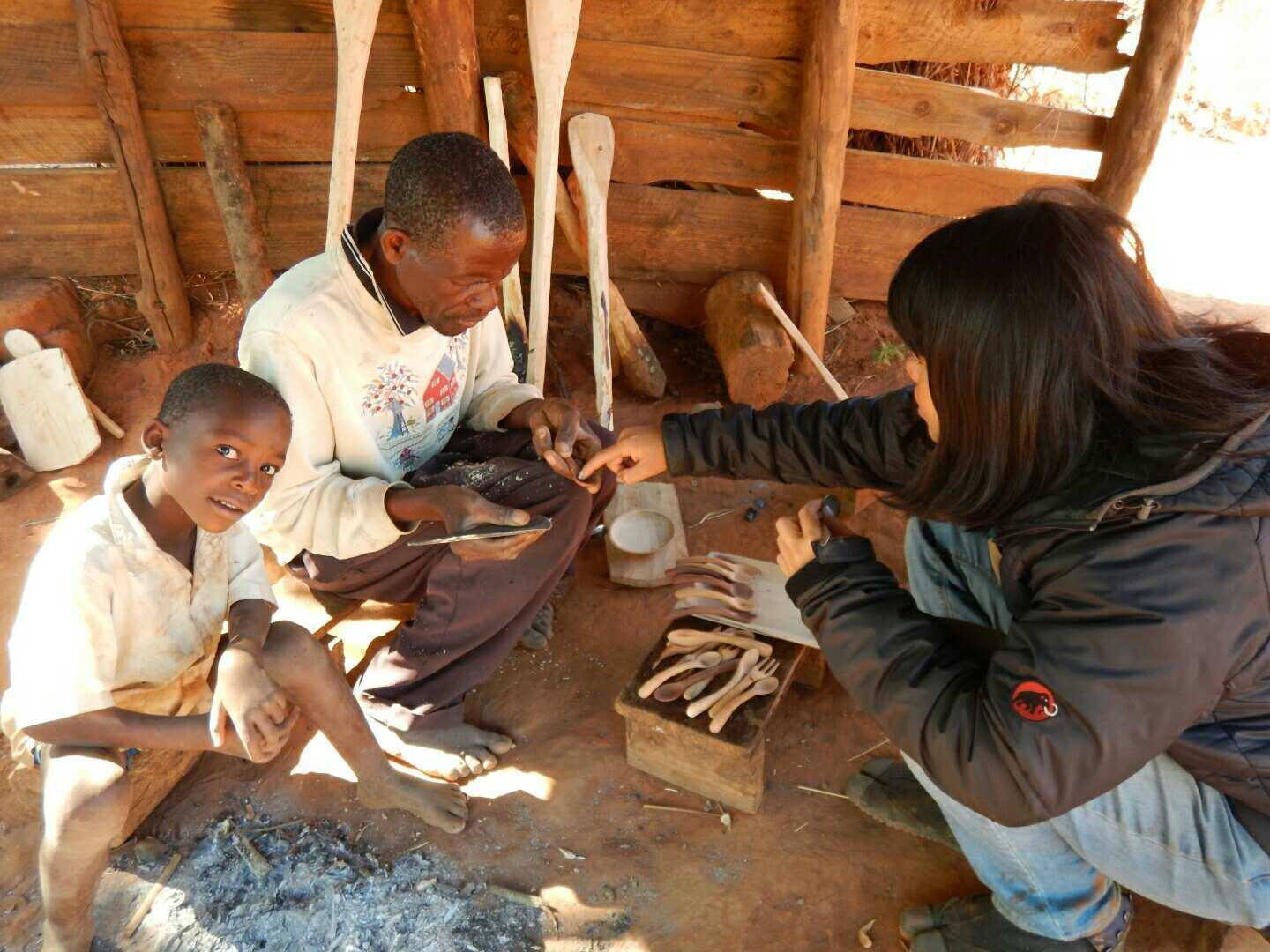 木工カトラリーの制作を担当する村人のもとを訪れ、改良点を説明する徳竹さん（写真右）