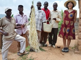 ラフィア椰子の葉で編んだバッグを持って笑顔を見せるブルンジの職人たちとドゥサベ友香さん（右）