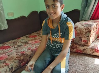 シリア難民のバーゼルくん。オンラインの補習授業を受けて、笑顔を見せる（写真提供：ワールド・ビジョン・ジャパン）