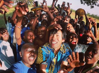 ケニアの更生学校の子どもたちと弾ける笑顔で写真を撮る望月さん（写真中央）
