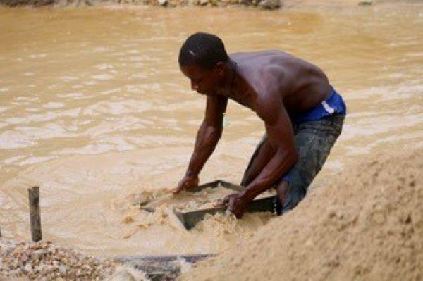リベリア西部のバポル州ウィズア村で働くダイヤモンド採掘労働者。川の土砂を大きな器ですくい、ダイヤの原石を探す（ダイヤモンド・フォー・ピース提供）