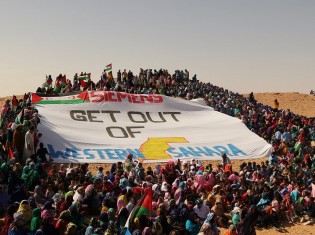 サハラーウィが避難するアルジェリア難民キャンプでの抗議行動。バナーには「シーメンスは西サハラから出ていけ」と書かれている（写真提供：ウエスタンサハラ・リソース・ウォッチ）