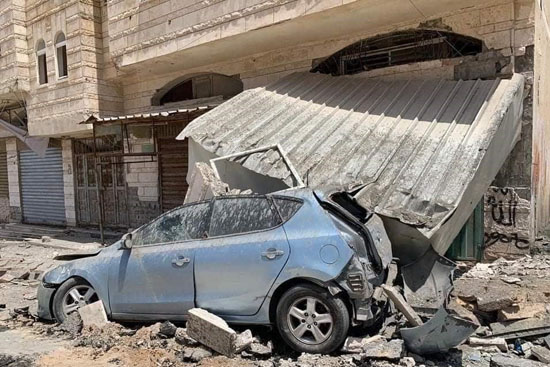 ガザ地区で建物が崩壊し、つぶれる車（写真提供：パルシック）
