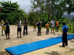 ジャマイカの貧困層の子どもたちが練習しているところ。孤児院やコミュニティセンターでの出張授業では外にマットを敷いて体操をする