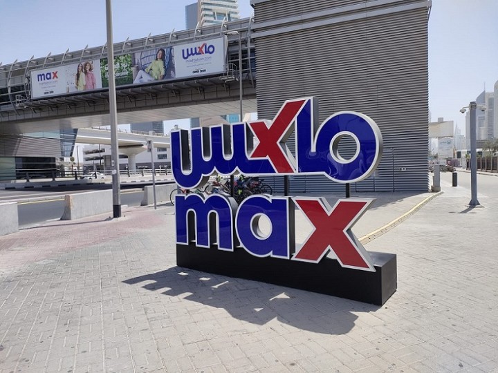 マックス駅の前にある、衣料品チェーン店MAXのロゴの模型。奥の駅舎にも広告がついている