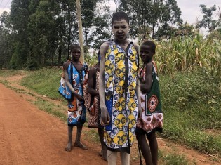ケニア南西部ブンゴマ地域のブムラで「伝統的な割礼」を終えて歩く男児たち。キテンゲと呼ばれる薄い布を上から被る。白色の土を体に塗り、長い歩きに備える男児（7月18日撮影）