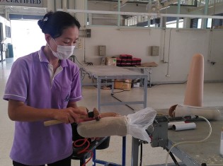 タイ北部のチェンマイにあるタイ義肢財団で働く国吉晃代さん。砂で作った義足の型に修正を加える