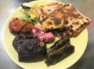 酸味と辛味の中にうま味を感じるクルド料理の数々。上から時計回りに、ナンのような生地で具を挟んだ「クロール」、タマネギやトマトを混ぜたご飯をぶどうの葉で巻いて煮込んだ「サルマ」、乾燥した赤ピーマンやナスにサルマの中身を詰めた「ドルマ」。中心にあるのは鮮やかなピンク色のピクルス