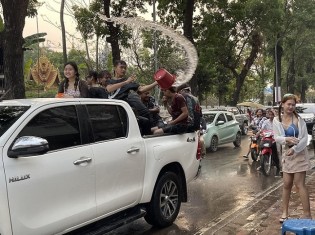 ラオスの若者たちがピックアップトラックを乗り回し、荷台から通行人に水を浴びせかける（首都ビエンチャン中心部の大通り）