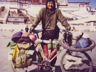 チベットのラサにあるポタラ宮殿の前で撮った記念写真。チベット建築家の平子豊さんは1998年、新疆ウイグルのカシュガルからラサまで2700キロの道のりを自転車で走破した（写真は本人提供）