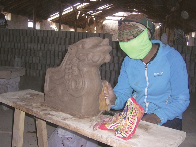 職人たちの仕事を増やして伝統技術が継承されるように、と平子さんは願う。写真はモンゴル南ゴビ州ノムゴン村で龍をモチーフにした装飾瓦を仕上げるモンゴル人の女性職人（写真は平子さん提供）
