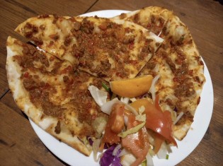 クルド風ピザの「ラフマジュン」。薄めの生地にひき肉やトマトを混ぜた具を乗せて焼き上げる。クルド人の大半が暮らす中東では定番の料理。フェスの当日は、在日クルド人が手作りしたラフマジュンなどの家庭料理が食べられる